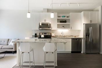 A modern kitchen with white cabinets and a marble island.